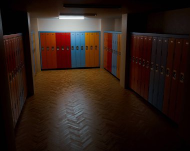 Ahşap zeminli loş bir soyunma odası ve duvarları renkli dolaplarla donatılmış bankalar.