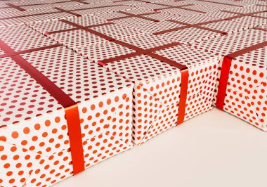 A collection of different sized rectangular gift boxes wrapped in polka dot red gift wrap paper with a red ribbon laid out flat on an isolated studio background - 3D render