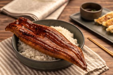 Yakın plan Japon ızgara yılanbalığı pilav ya da Unagi Don tabakta servis edilir. Restoran masasında Japon yemeği.