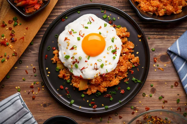 Kimchi Fried rice topped with fried egg and fresh kimchi cabbage in a bowl on placed wooden background. Korean food style