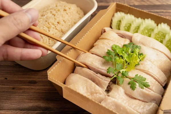 Hainanese Chicken rice (Singapore chicken rice) famous singapore food and Thai food on dark wood table. Asian food style.