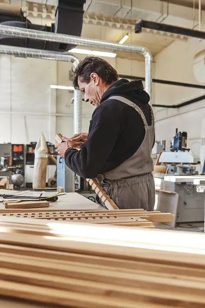 Focus on quality. Carpenter using chisel to carve wood in workshop