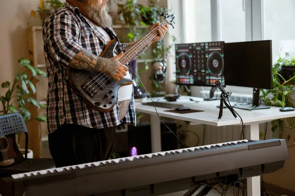 Composer plays electric guitar recording track in home audio studio closeup
