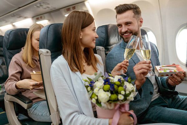 Happy couple toasting with champagne glasses in airplane