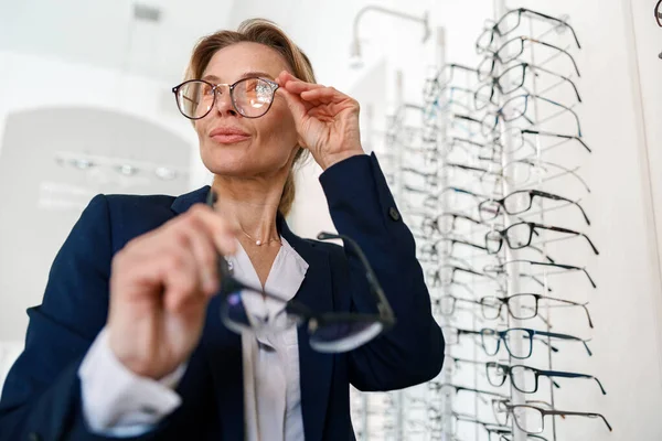 Middle-age businesswoman buys glasses in an modern optical store