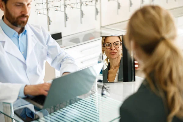 An ophthalmologist consults a client at his workplace in an opticians shop. High quality photo