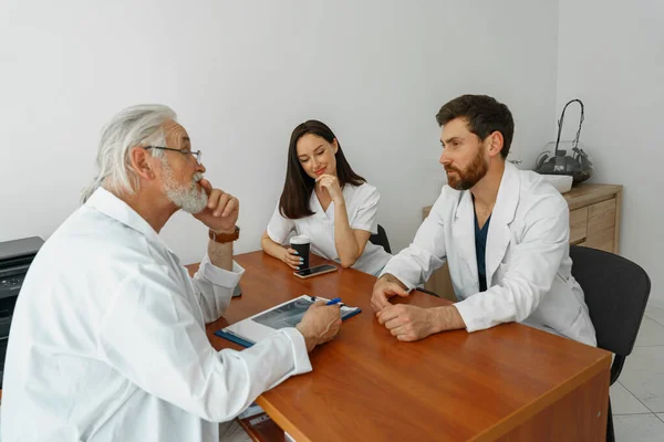 Group of doctors sitting at meeting table in conference room during medical seminar. High quality photo