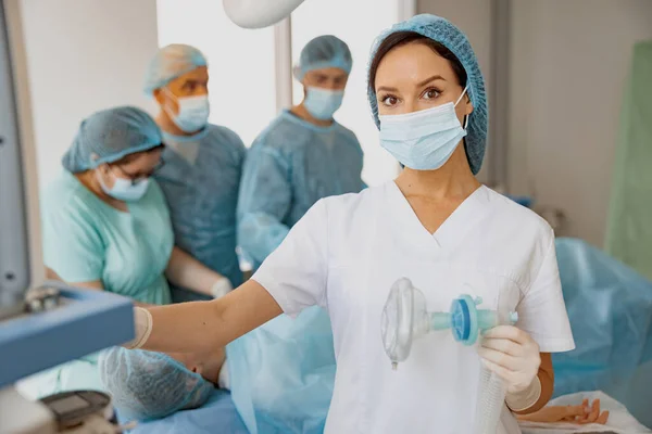 Nurse holding mask for anesthesia standing with colleagues on background. High quality photo