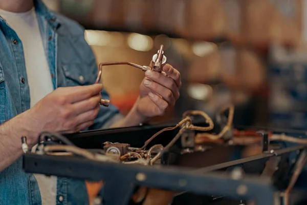 Close up of man hands repairing coffee machine in a workshop and holding some necessary details