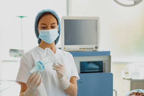 Focused nurse holding mask for anesthesia standing in operation room. High quality photo