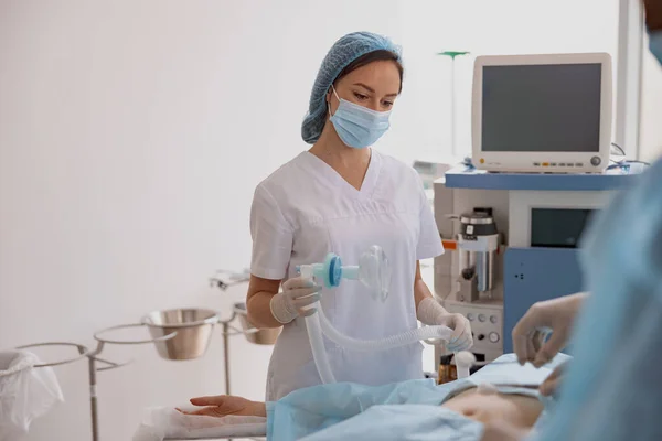 Nurse holding breathing mask during operation in clinic. Withdrawal from anesthesia