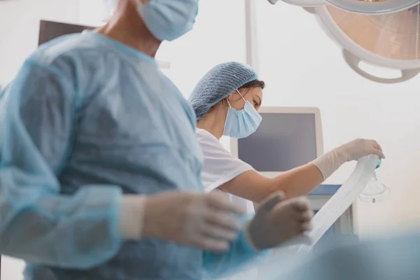 Nurse holding mask for anesthesia standing with colleagues on background. High quality photo