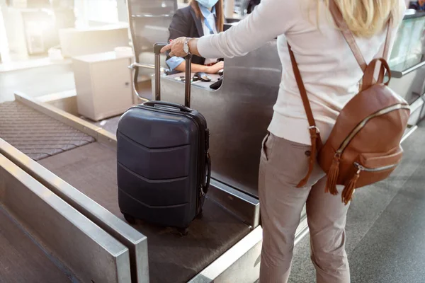 Cropped photo of woman with backpack weighing luggage at airport check in