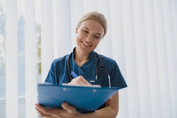 Woman doctor taking notes on clipboard during appointment in medicine center. High quality photo