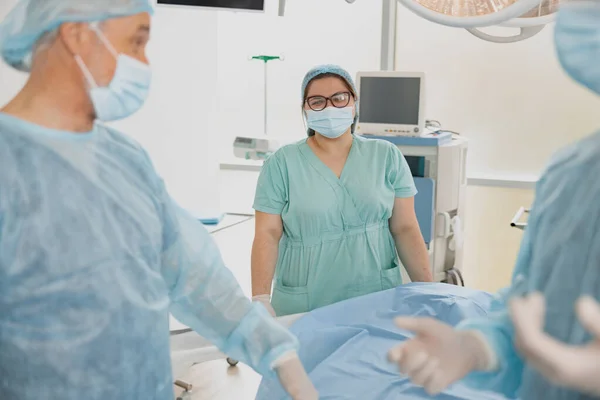 Nurse assisting doctors during surgery in operation room of modern clinic. High quality photo