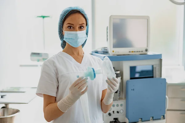 Focused nurse holding mask for anesthesia standing in operation room. High quality photo