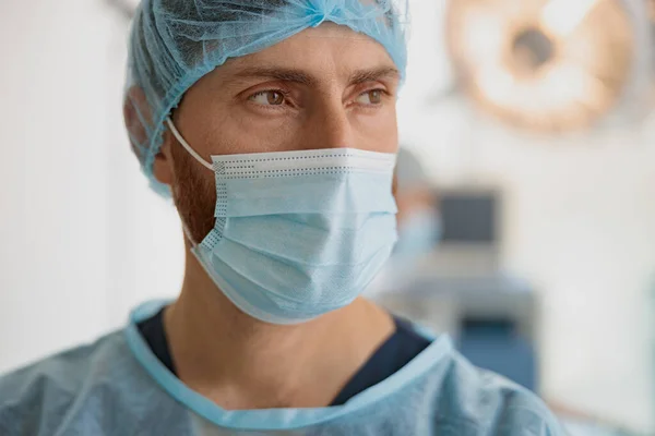 Close up of doctor in mask standing in operating room before surgery. High quality photo