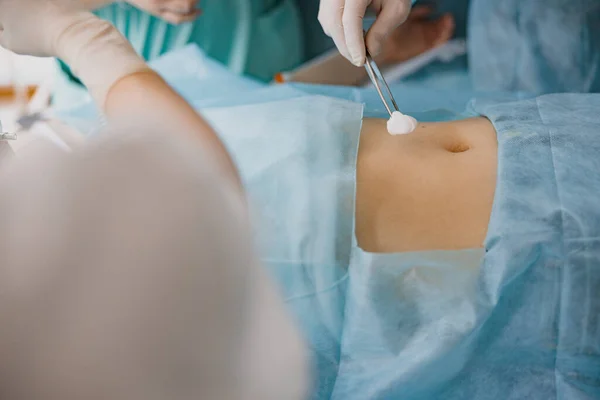 Nurse and doctor prepare patient skin for surgery using antiseptic solution in operation room