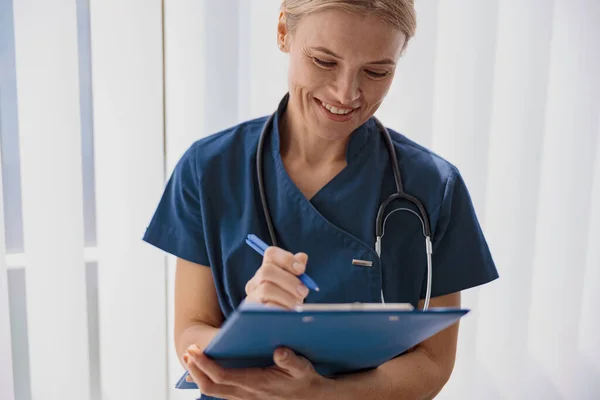 Woman doctor taking notes on clipboard during appointment in medicine center. High quality photo