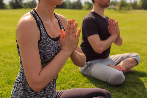 Young healthy man and woman doing yoga in the sunny summer park. High quality photo