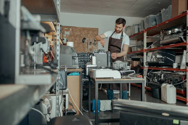 Man worker repairing coffee machine on own workshop. High quality photo