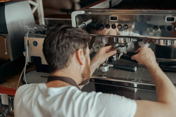 Man worker in uniform inspecting coffee machine in own workshop. High quality photo