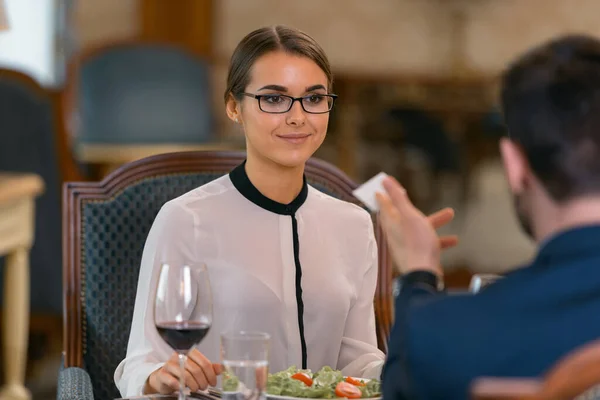 Businessman giving his visit card to woman in luxury hotel restaurant. High quality photo