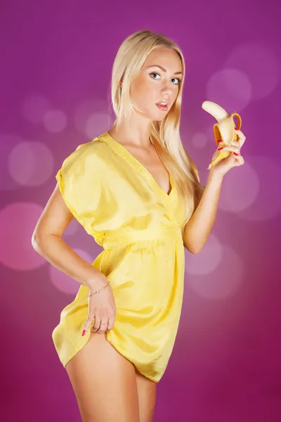 Ładny blond kobieta trzyma banana gotowy do jedzenia na różowy backgro — Zdjęcie stockowe