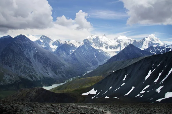 Ak-Kem river valley aerial view, alpine gorge, Belukha mountain in the background, mountain peaks are covered with snow, a river flows through the valley, summer sunny day, sky in the clouds, Altai