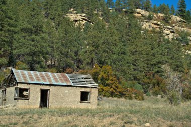 Terk edilmiş ev teneke çatılı çam ağaçlarının ve kireçtaşı kayalıklarının sığınağında oturuyor.