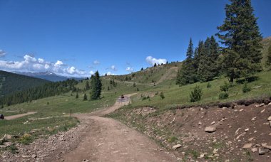 Red ATV on a mountain trail going thru standing water on a mountain top