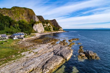 Kuzey İrlanda, İngiltere. Atlantik kıyısında uçurumlar, Causeway Coastal Route, evler, kamp ve Garron Point 'te jeolojik kaya oluşumu. Gün doğumunda hava görüntüsü