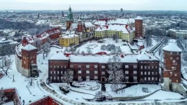 Polonya 'nın Krakow kentindeki tarihi Wawel Kalesi ve Katedrali' nde Vistula Nehri ile yürüyen insanlar, kışın kar ve gezinti güvertesi. Hava görüntüleme videosu
