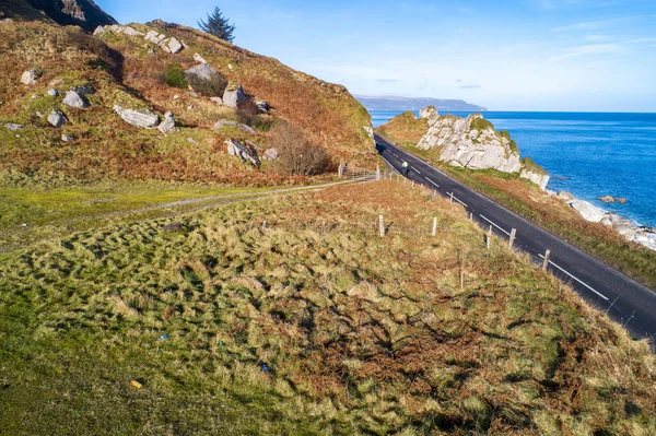 The eastern coast of Northern Ireland and Causeway Coastal Route with a cyclist. One of the most scenic coastal roads in Europe. Aerial view in winter