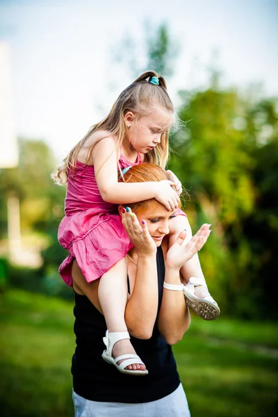 Mother and daughter on a piggyback in park — Stock Photo, Image