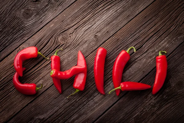 Chili sign with fresh chillies on a wooden table — Stock Photo, Image