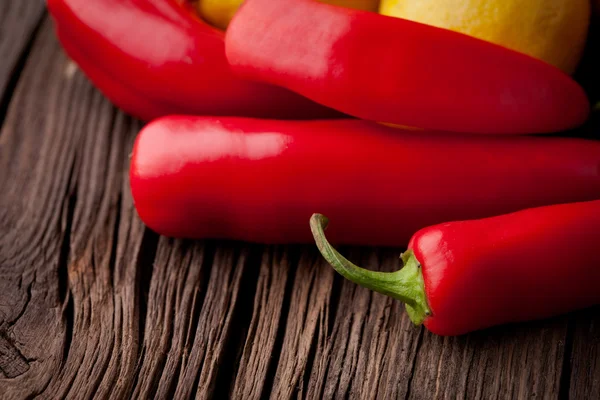 Färsk röd chili och citroner på ett träbord — Stockfoto