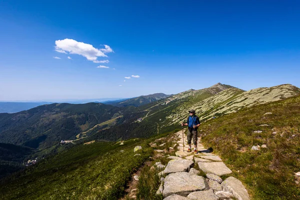 Senior man on a path around Chopok and Dumbier mountain with Stefanika shelter  - in slovakian low Tatra mountains. Summer panorama with great weather and blue sky