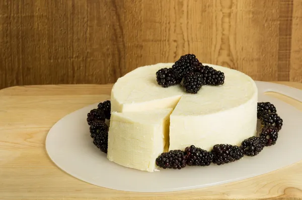 Fresh white cheese cut with black berries — Stock Photo, Image