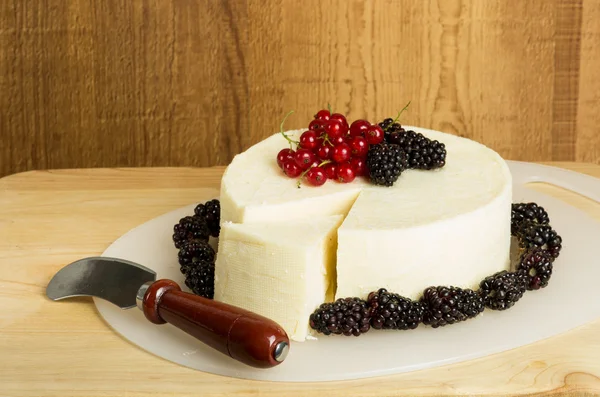 Round of white cheese decorated with currants and berries — Stock Photo, Image