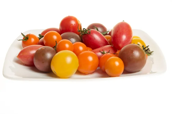 Fresh mixed tomatoes on white plate — Stock Photo, Image