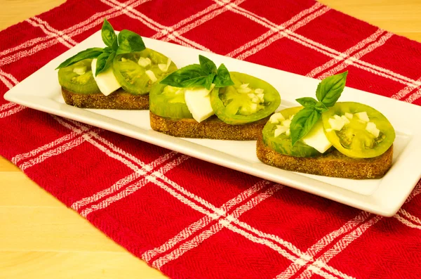 A zöld családi ereklye paradicsom sajtos- bazsalikomos friss bruschetta — Stock Fotó