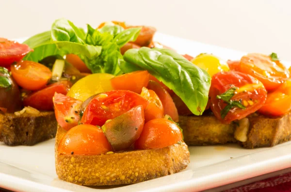 Fresh bruschetta with mixed tomatoes cheese and basil on plate — Stock Photo, Image