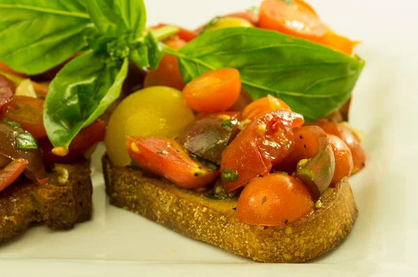 Fresh bruschetta with mixed tomatoes cheese and basil — Stock Photo, Image