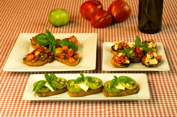 Fresh bruschetta with tomatoes cheese basil and wine bottle — Stock Photo, Image