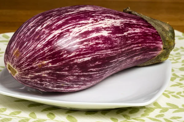 Colorful striped eggplant on white plate — Stock Photo, Image