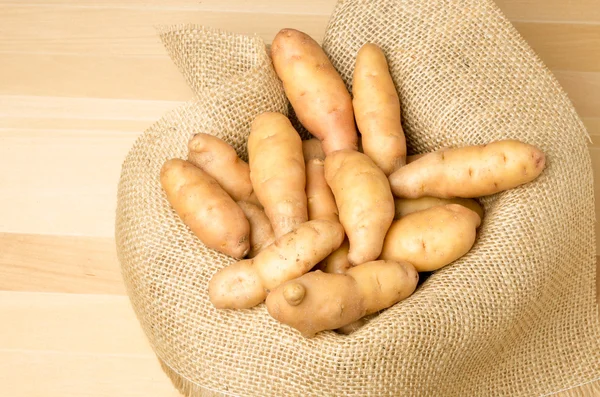 Batatas com dedos em saco de serapilheira — Fotografia de Stock