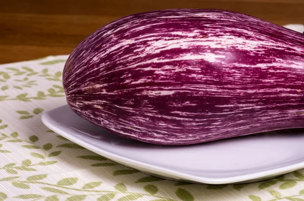 Пурпурные полосатые баклажаны на белой тарелке — стоковое фото