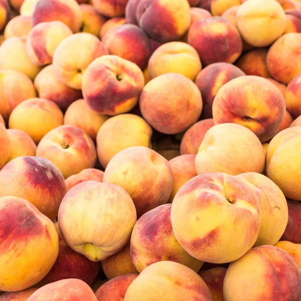 Дисплей свежих желтых персиков — стоковое фото