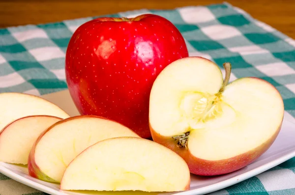 Красное яблоко нарезано на тарелке — стоковое фото